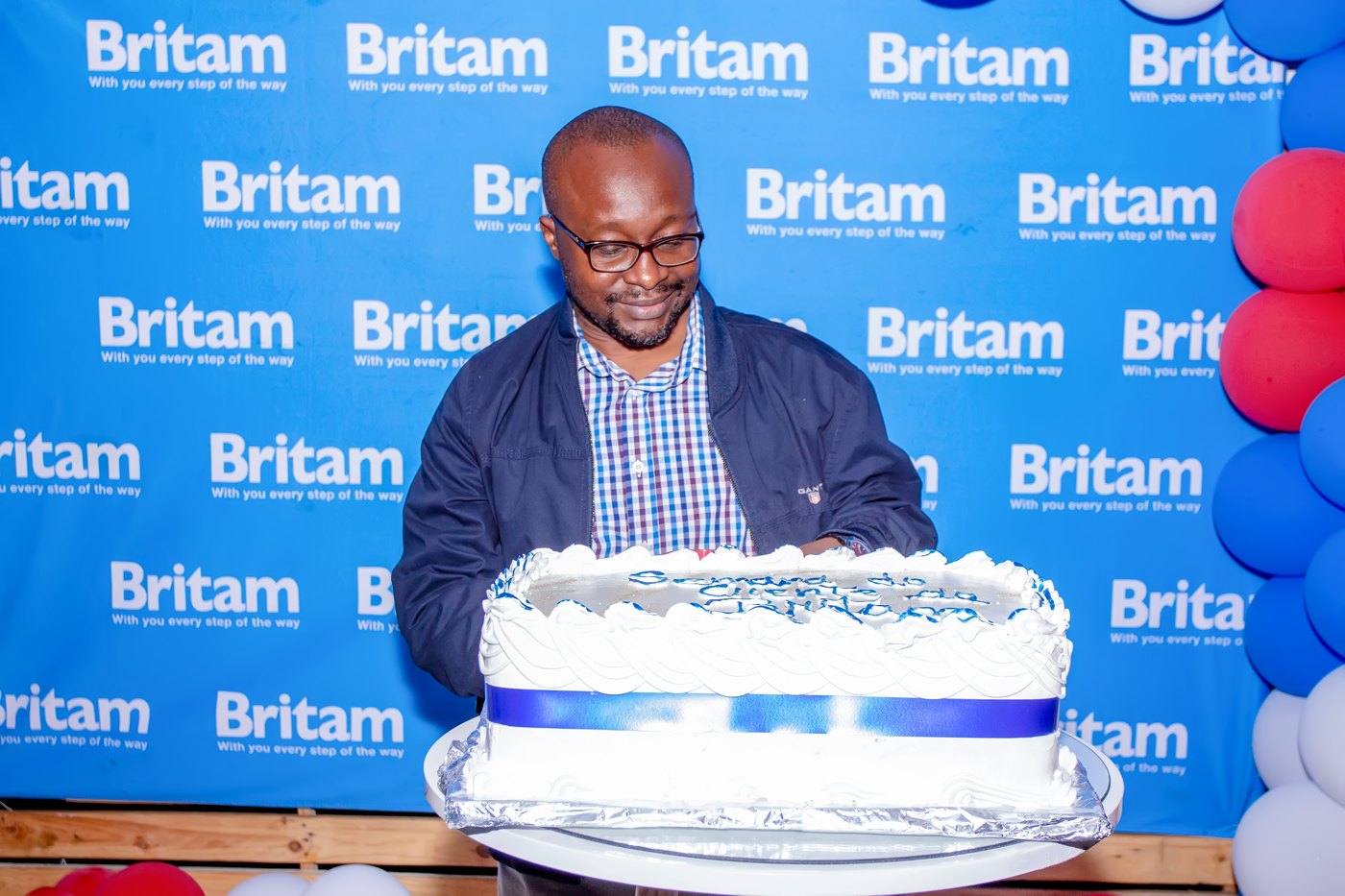 Britam-branded backdrop and celebration cake